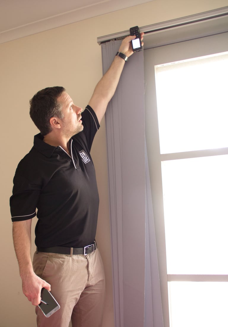 Black-and-white BWK Group quantity surveyor using a laser measure during an internal property inspection